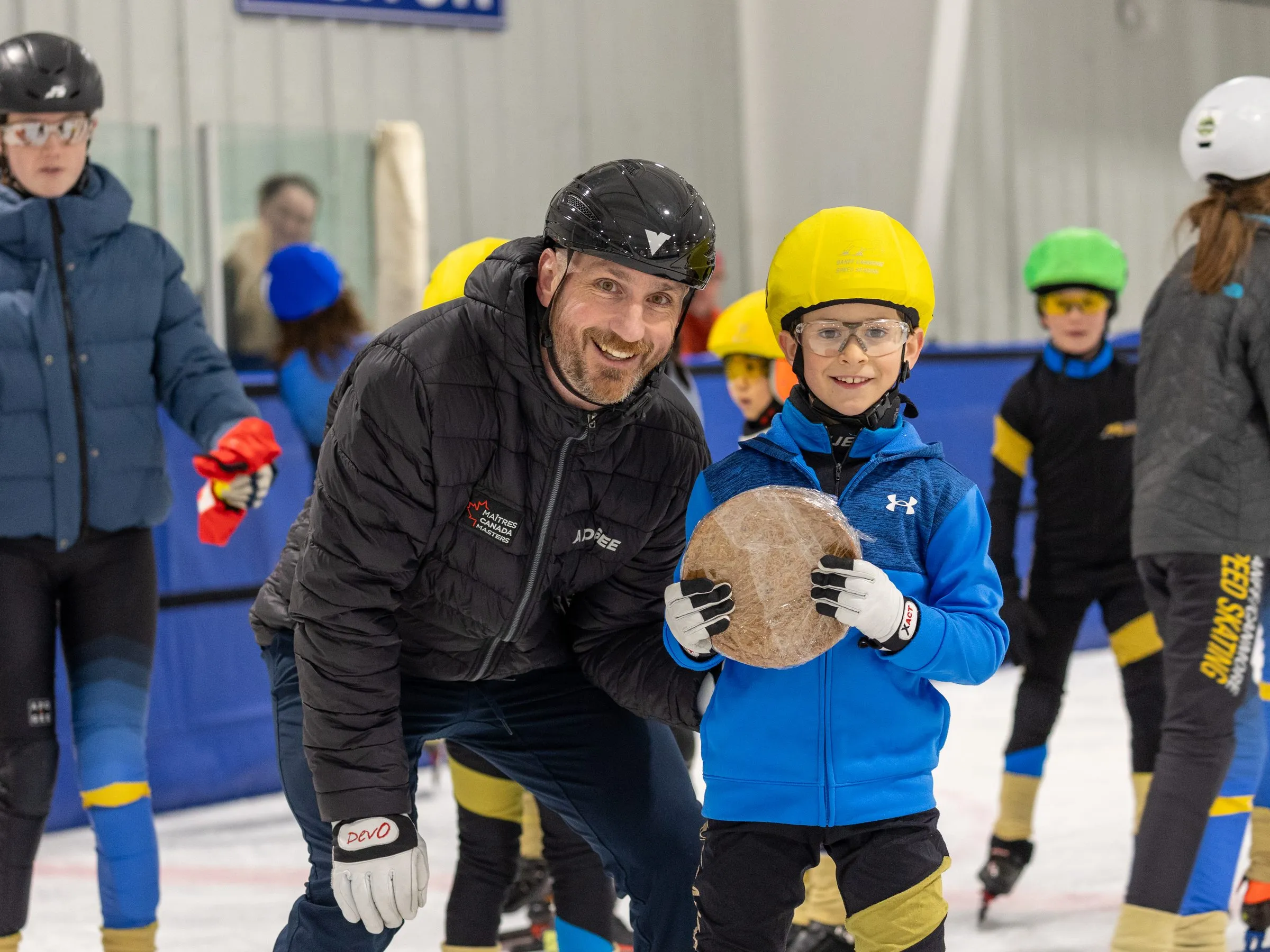 A coach presenting a skater-of-the-month award on the ice