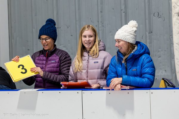 Parents rink-side holding up lap count cards